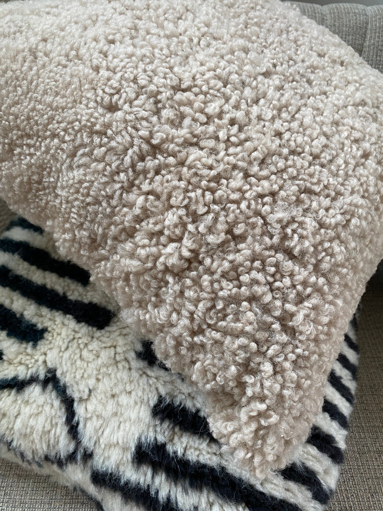 Edge-view of tan shearling sheepskin pillow