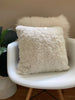 Iivory shearling sheepskin pillow on a white chair 