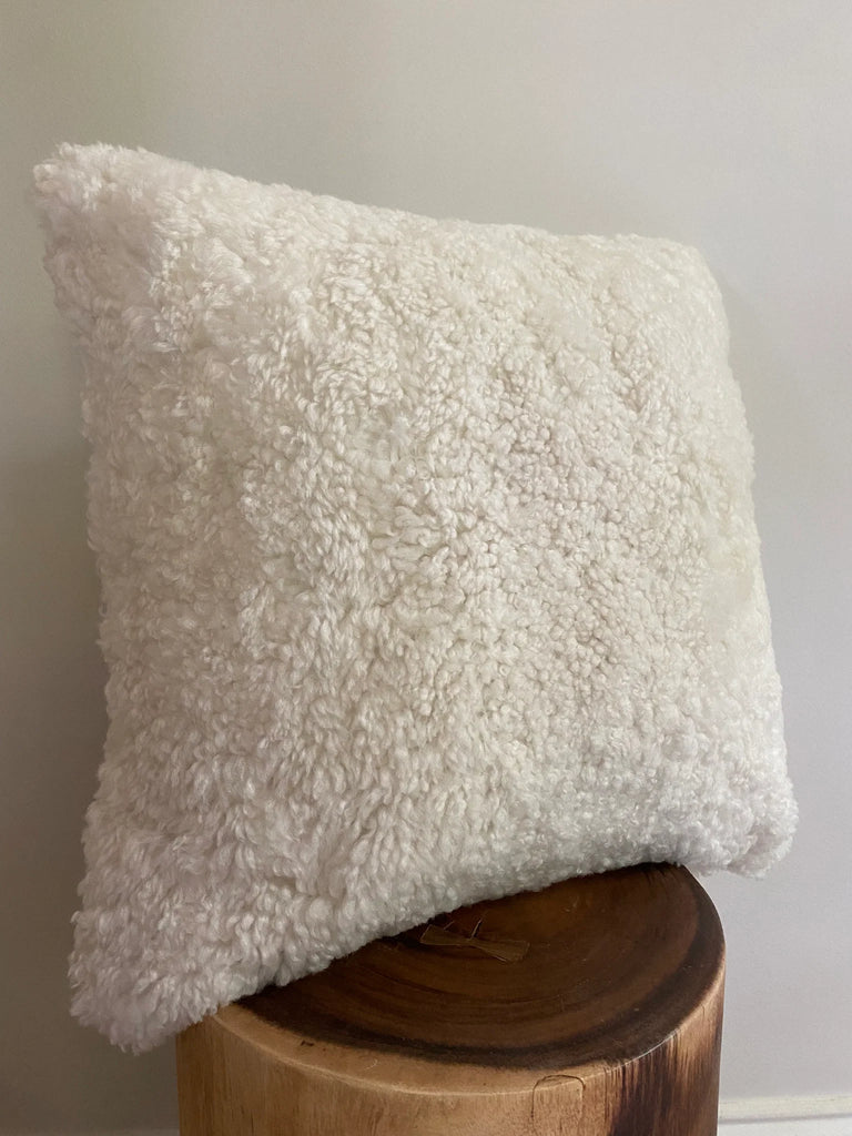 ivory shearling sheepskin pillow on a wooden block 