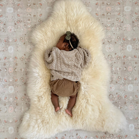 Baby lying on a bright ivory nursery sheepskin