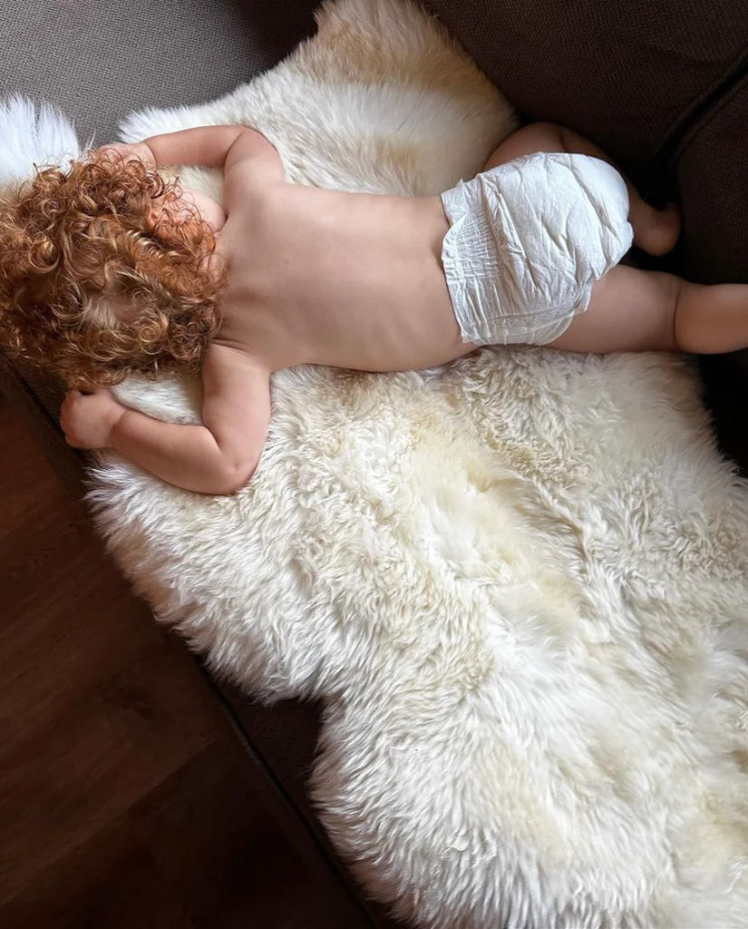 Baby lying on a bright ivory nursery sheepskin
