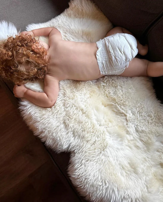 Baby lying on a bright ivory nursery sheepskin