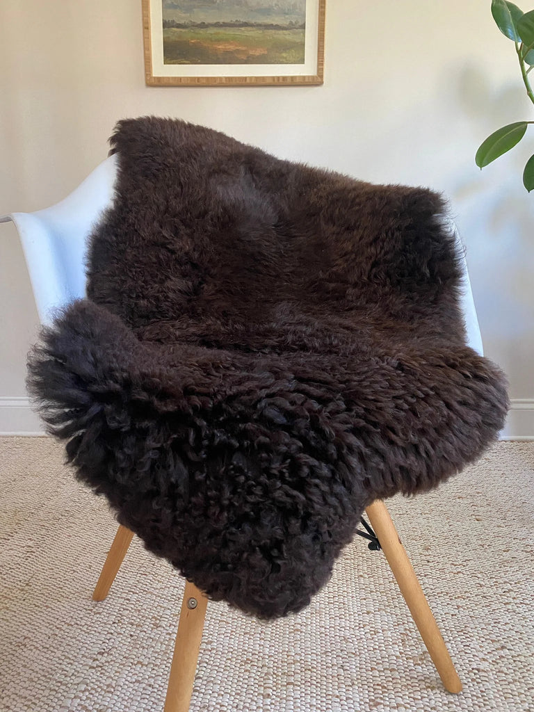 Dark Brown sheepskin rug draped over a chair 