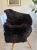 Dark Brown sheepskin rug draped over a chair 