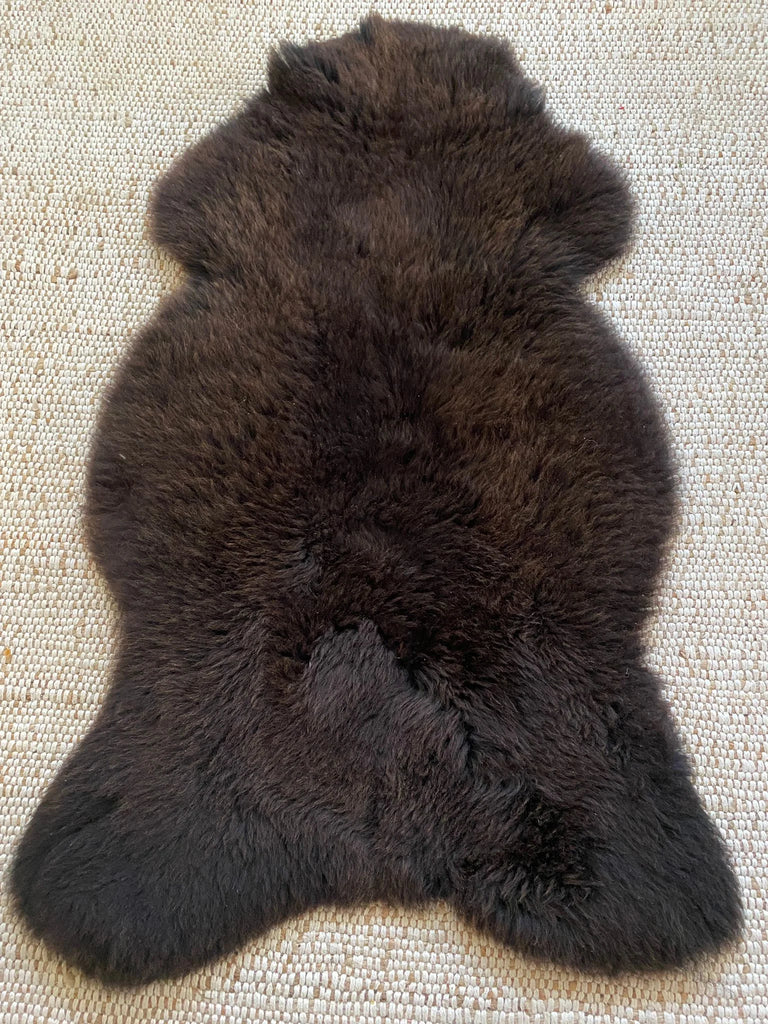Top view dark brown fur rug on a textured surface