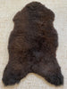 Top view of dark brown fur rug on a textured surface