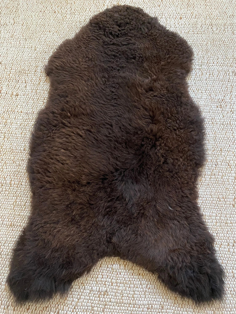 Top view of dark brown fur rug on a textured surface