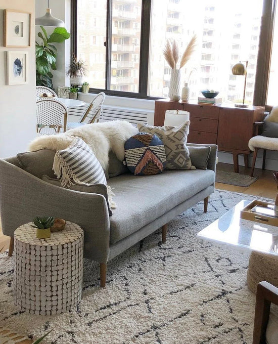 Living room with a gray sofa, patterned cushions, and classic ivory sheepskin