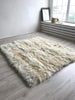 Creamy ivory sheepskin bed cover rug on a wooden floor 