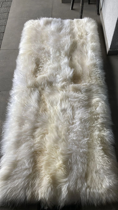 Top-view of creamy ivory sheepskin bed cover rug