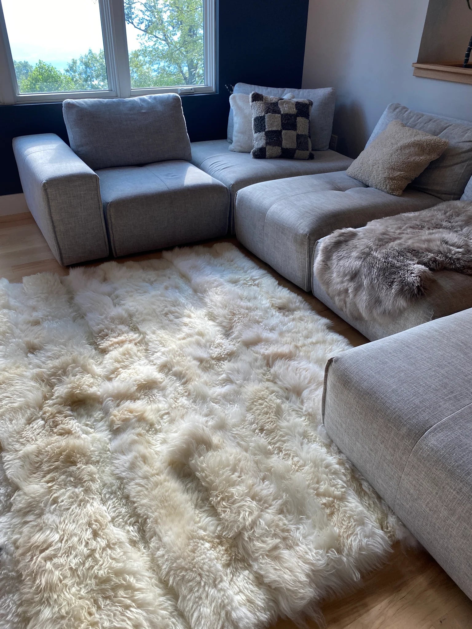 Gray sectional sofa with creamy ivory sheepskin bed cover rug