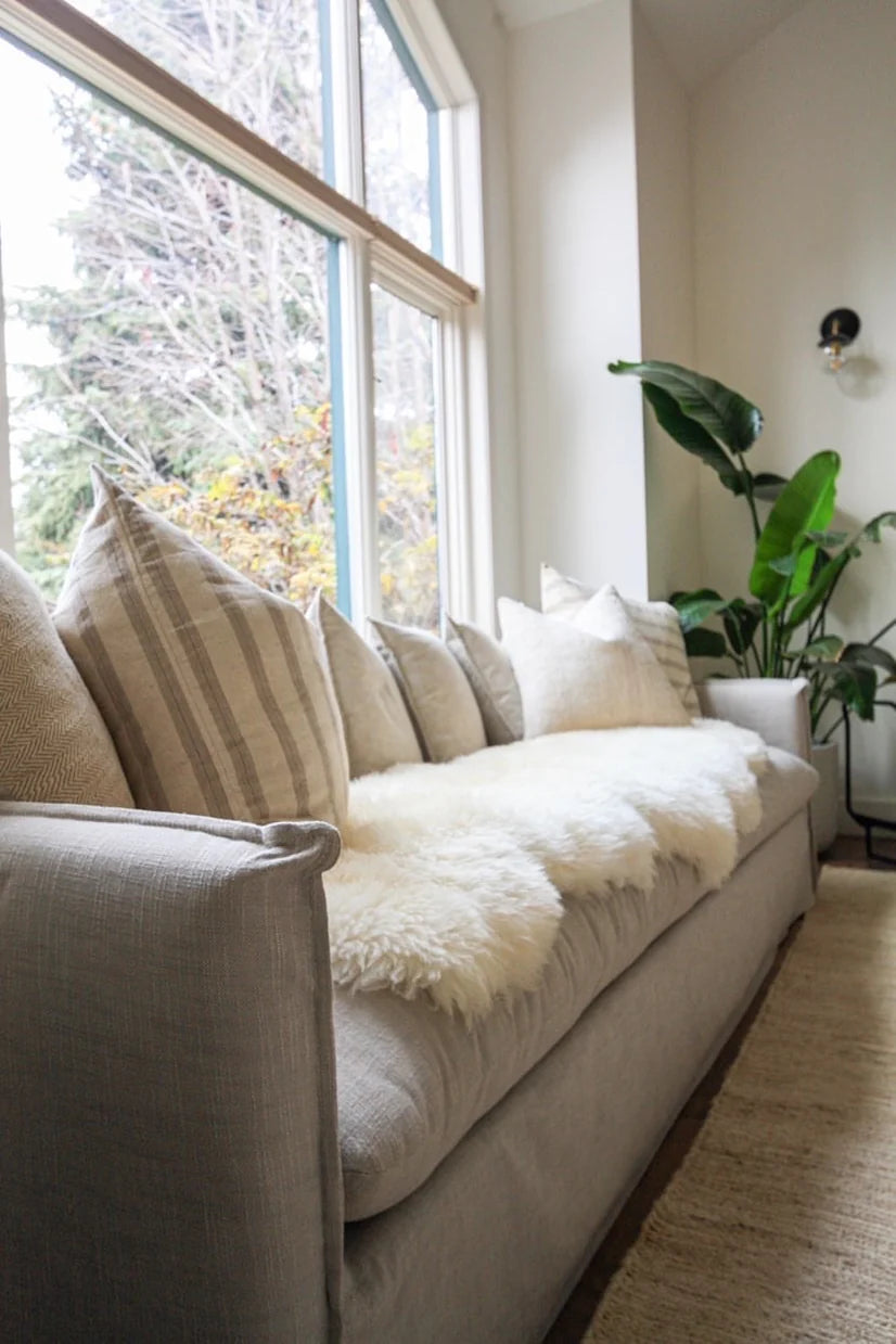 Beige sofa with decorative pillows with double sheepskin in white