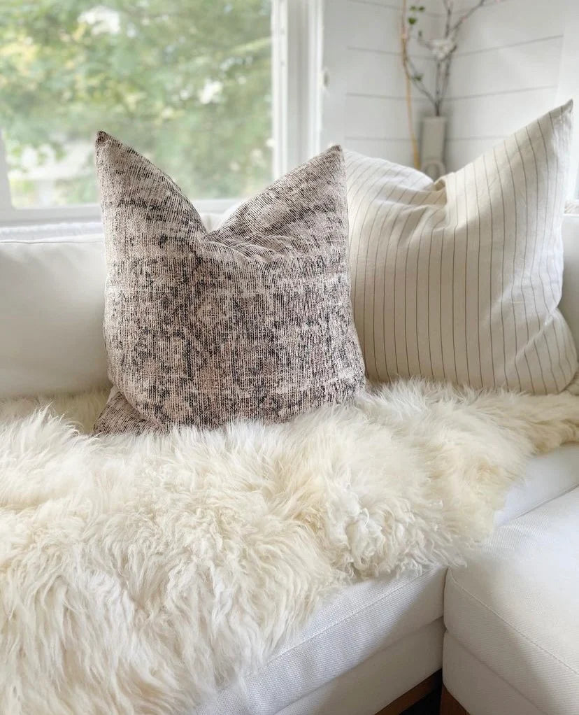 Decorative pillows on a white sofa with double sheepskin in white