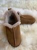 Tan slipper with fur trim on a fluffy white surface