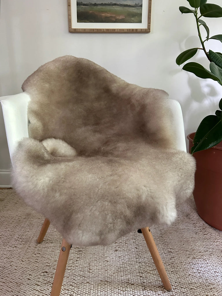 Greyish brown shortfur sheepskin over a chair 