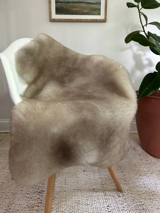 Greyish brown shortfur sheepskin over a chair