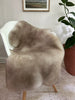 Greyish brown shortfur sheepskin over a chair