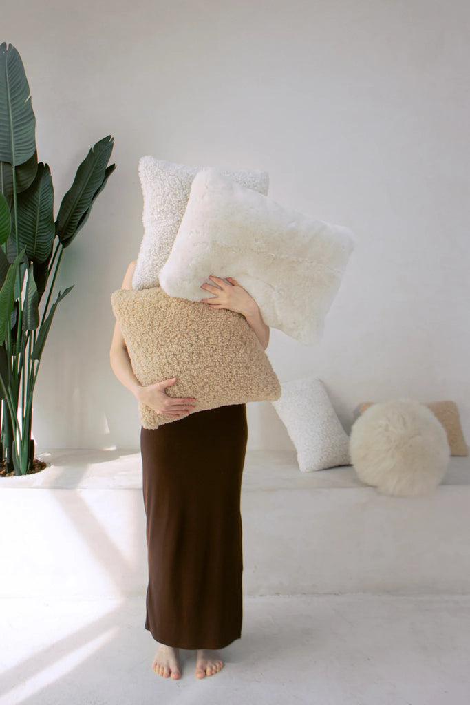 Person holding ivory shearling lumbar