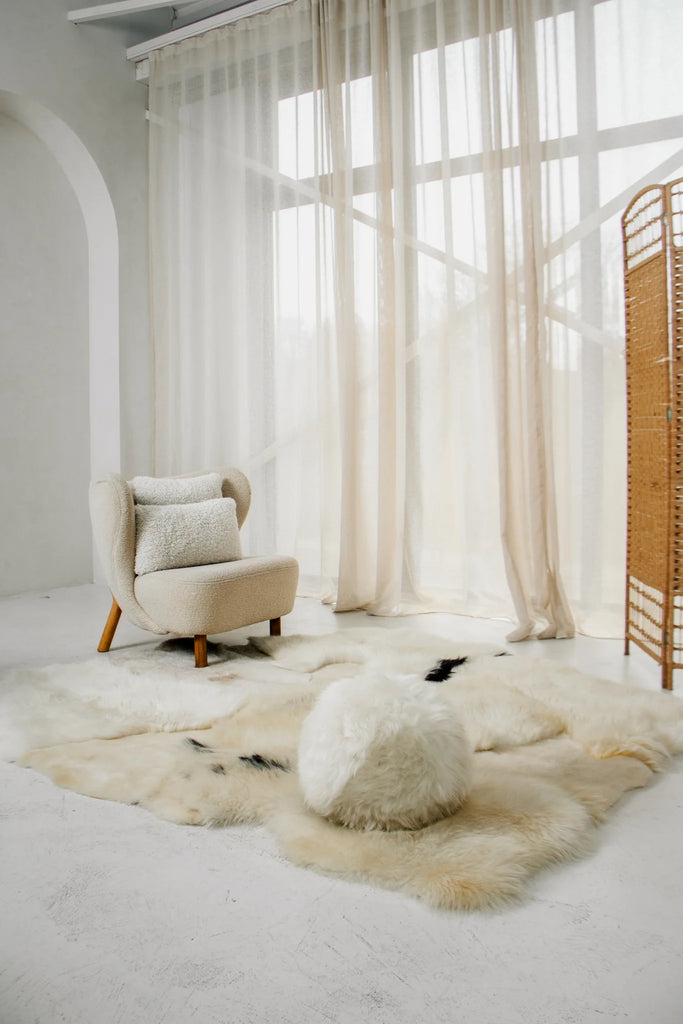 Modern interior with a chair, ottoman, and rug in a bright room with ivory shearling lumbar