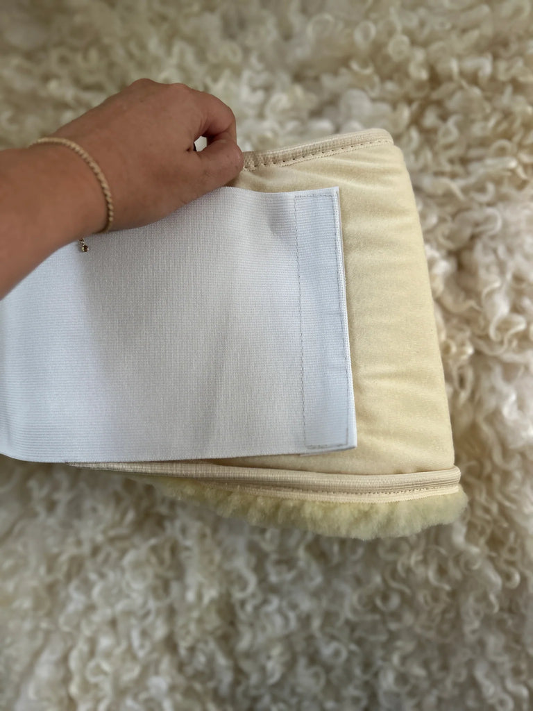 Hand holding a medical grade sheepskin kidney warmer and waist belt
