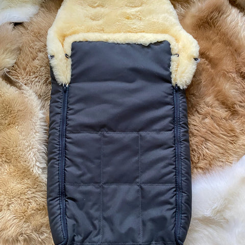 baby and toddler sleeping bag with cream sheepskin lining placed on a fluffy rug
