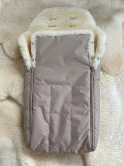 baby and toddler sleeping bag with cream sheepskin lining placed on a fluffy rug