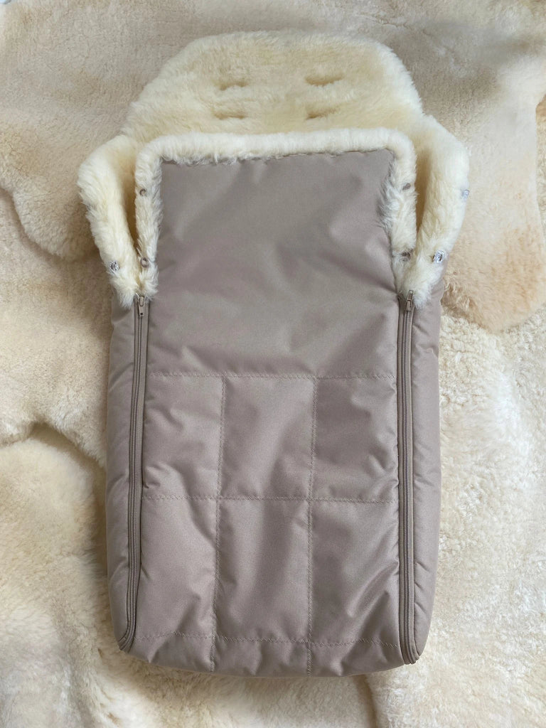baby and toddler sleeping bag with cream sheepskin lining placed on a fluffy rug