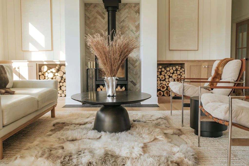 Close-up of modern living room with a sofa, armchair, coffee table, and mixed textured sheepskin rug