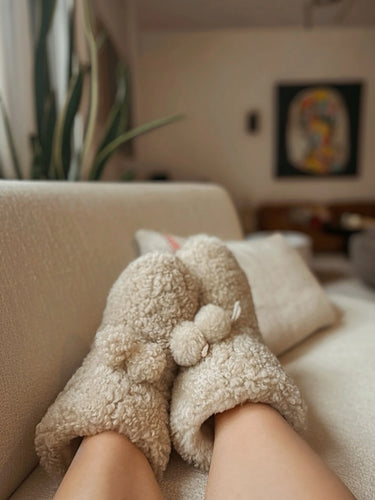 Person wearing organic sheepskin slippers on a couch 