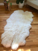 Plush quad pelt ivory sheepskin on a wooden floor 