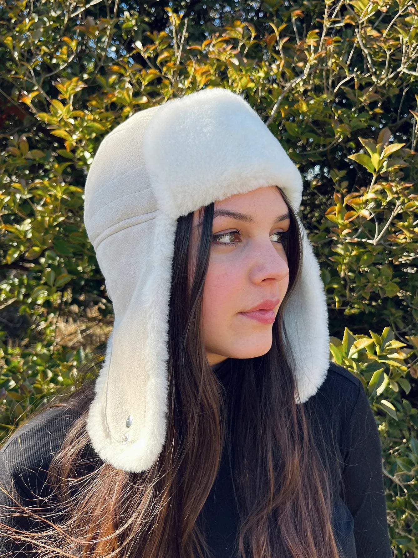 Person wearing a sheepskin and leather pilot hat in cream