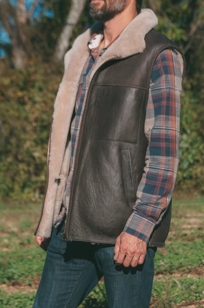Person wearing a leather sheepskin mens vest outdoors.