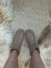 sheepskin slippers on a textured rug with fur border