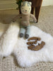 Knitted cat toy with wooden pieces on small white nursery pelt