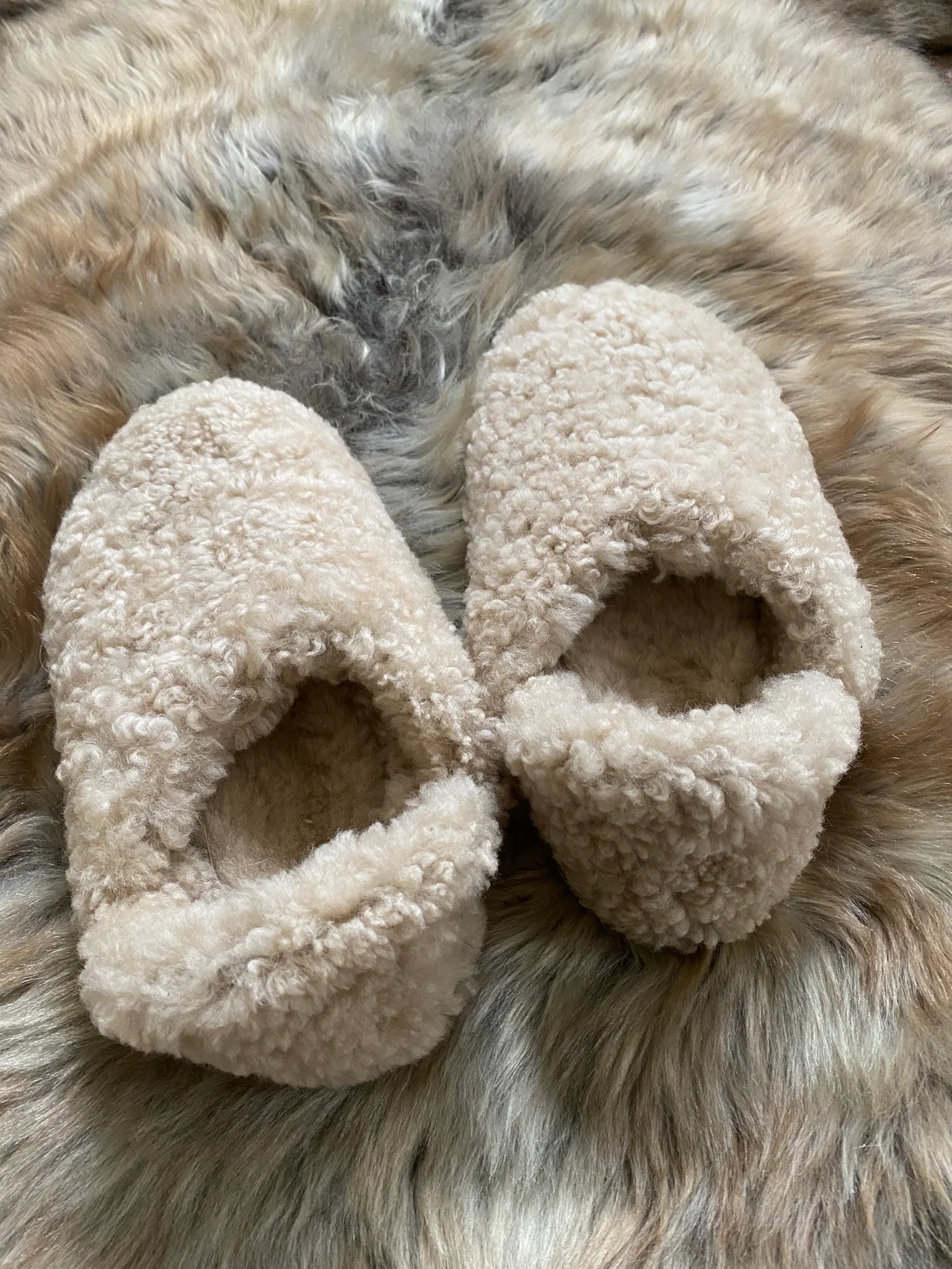 Pair of beige slippers on a fur surface
