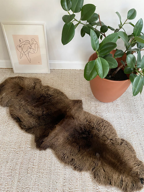 Vibrant brown double sheepskin on a beige carpet 